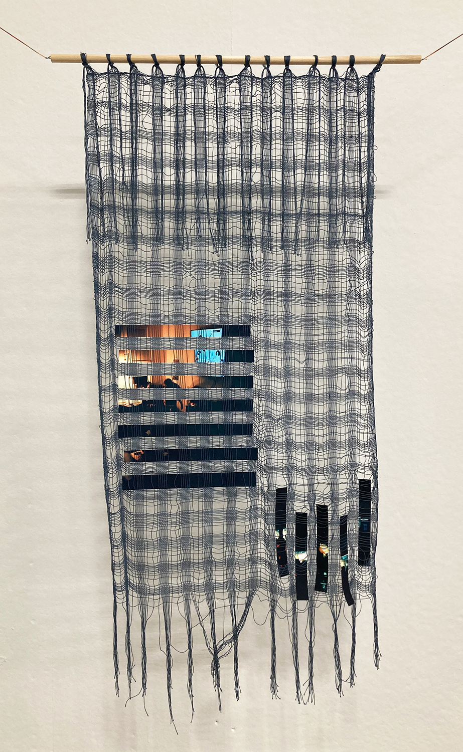Hanging yarn woven into loose fabric with a photograph woven through the yarn