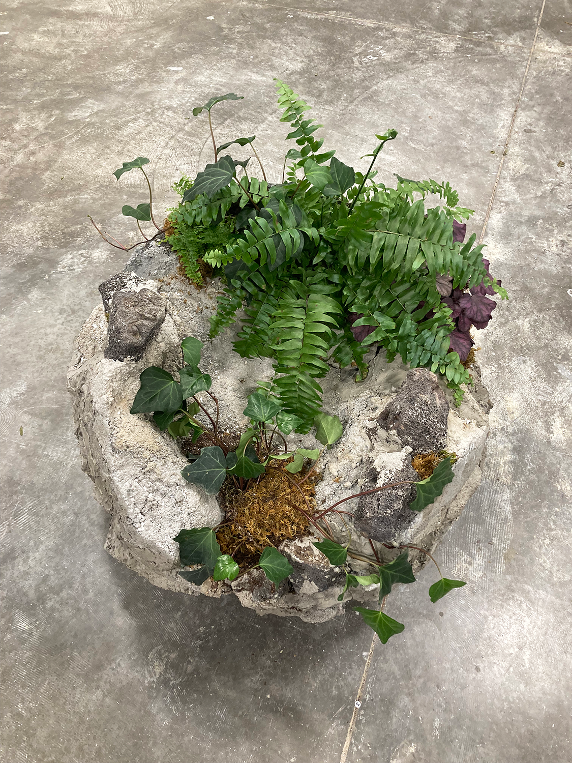 Sculpture of a rock made of concrete and plaster as well as organic materials. 