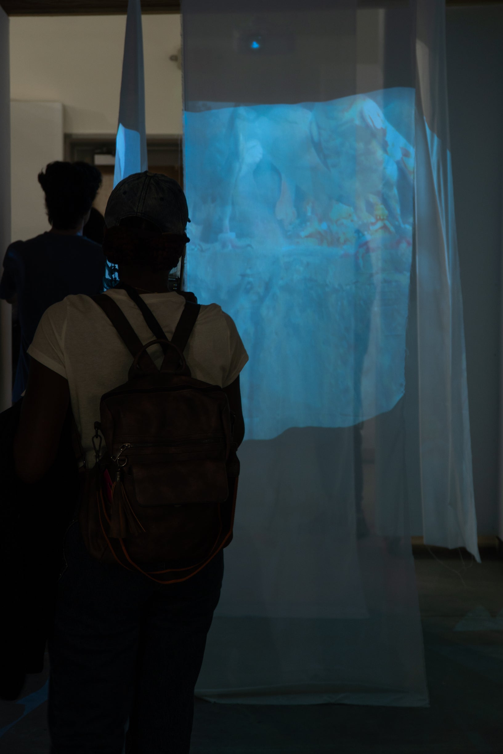 Photograph of someone in a space with projections by Abdullah J.