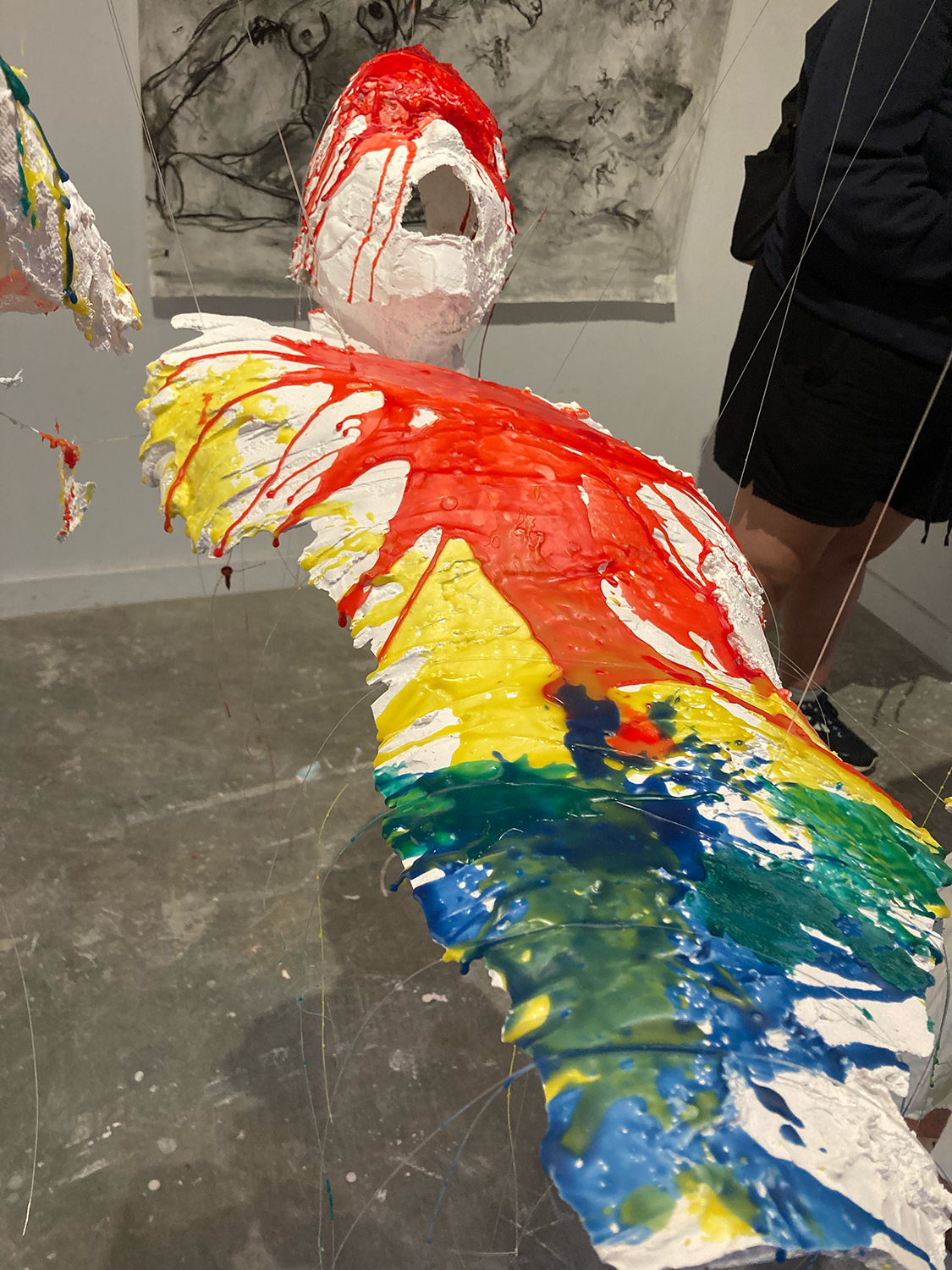 Alternate view of a body cast made of plaster with melted color wax, hanging in midair
