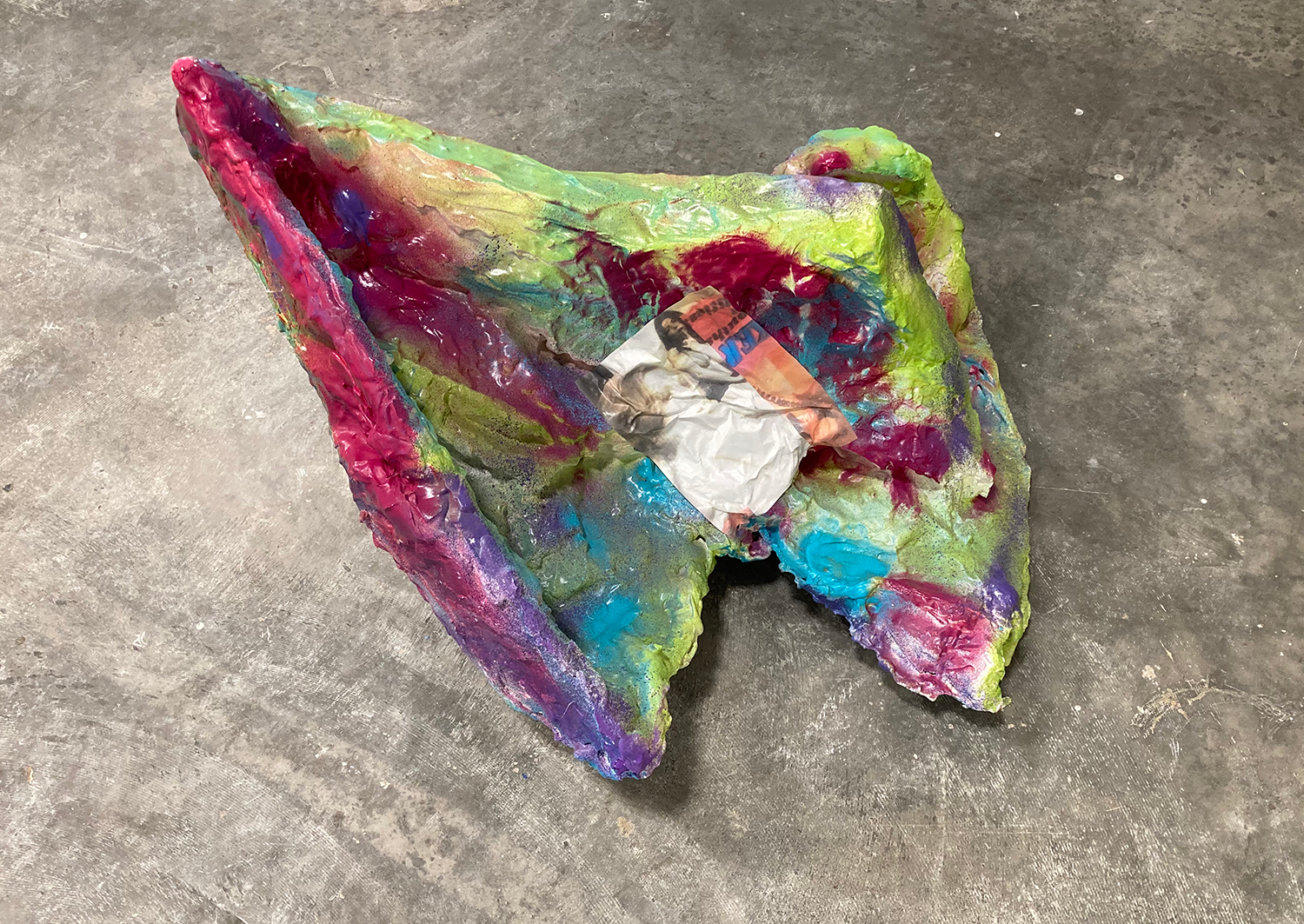brightly colored sculpture with magazine pages adhered 