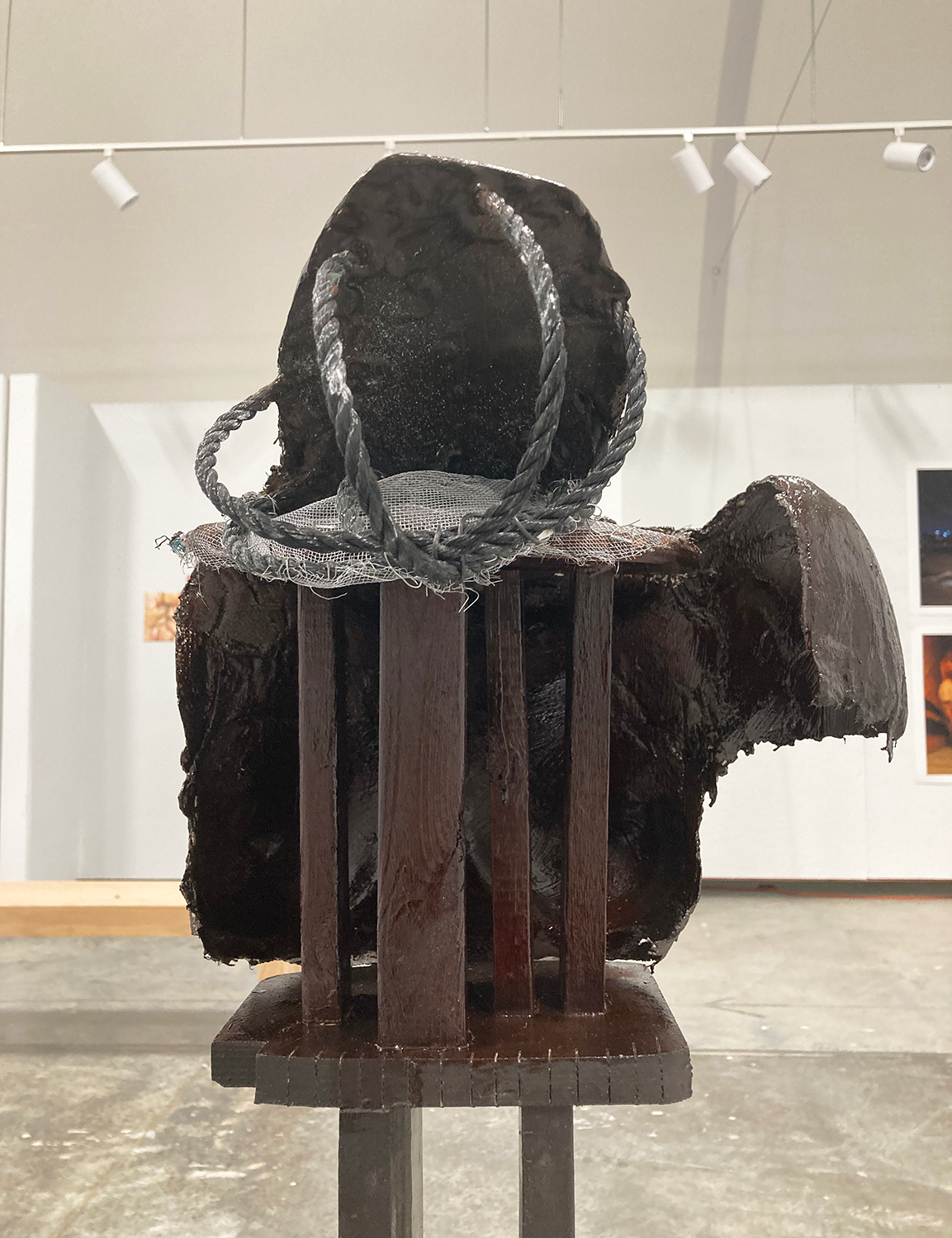 Sculpture of a bust with wire cables forming the head, seen from the back