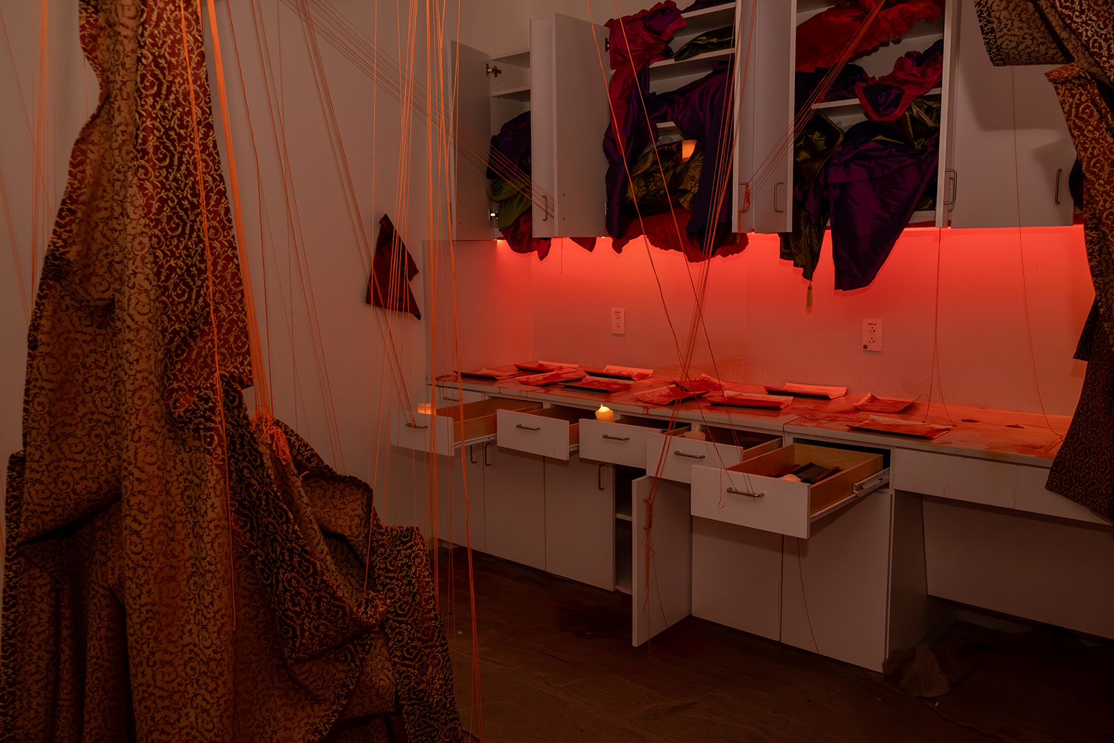 Image of a room filled with red material and yarn softly lit