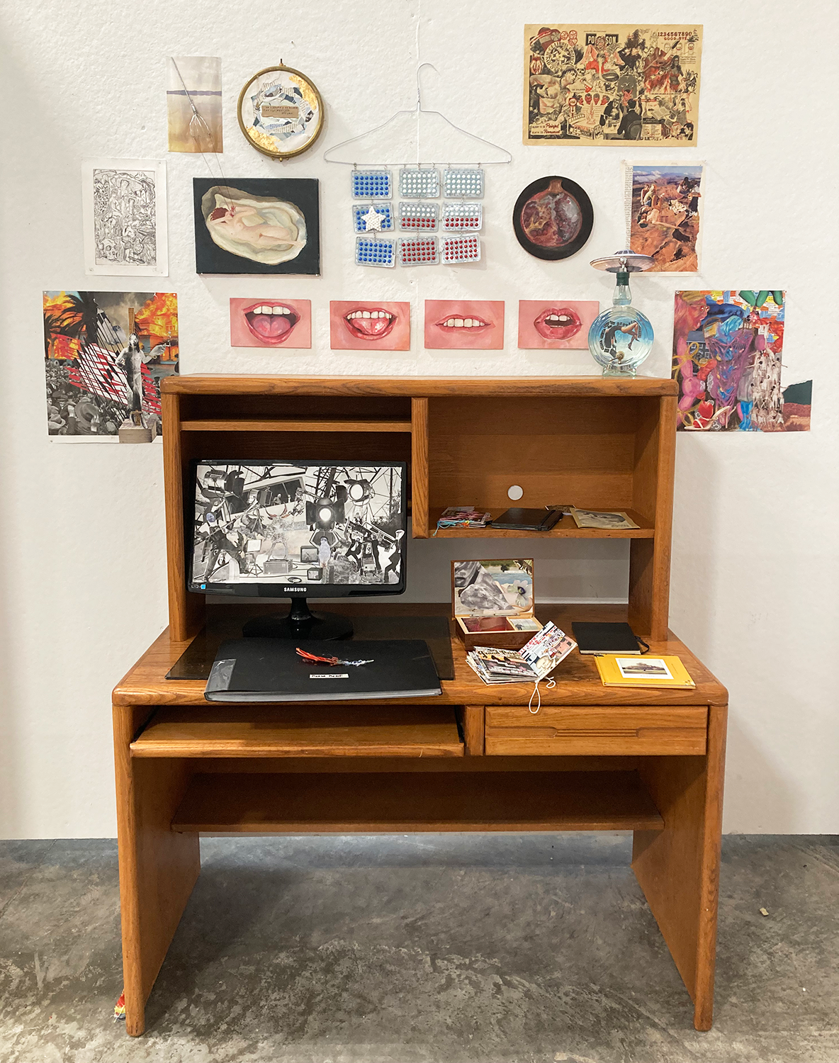 A scene of a desk space with art hanging above it, on it, and around it