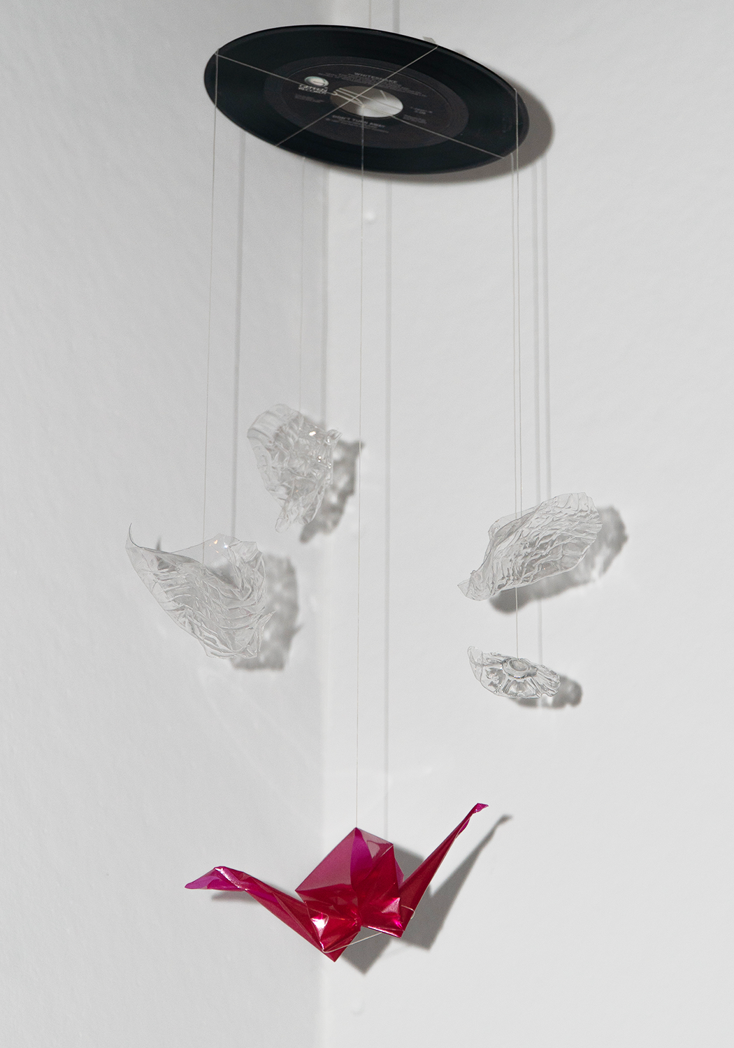 a record mobile with clear acrylic pieces and a mylar origami crane that's hot pink