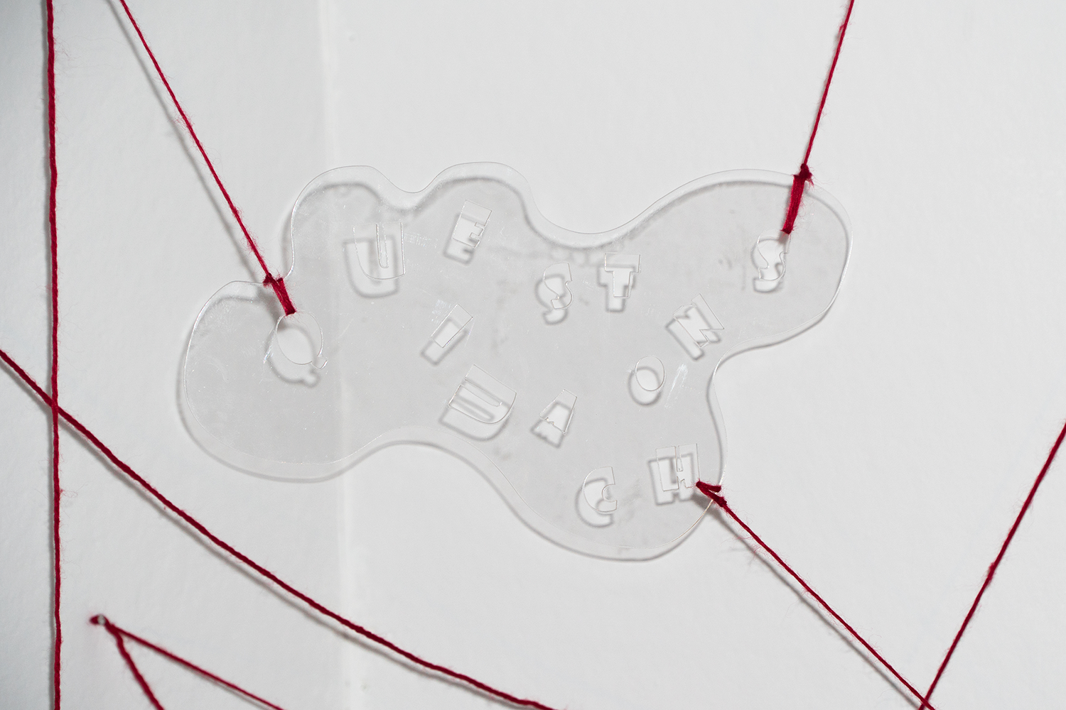 close up of clear acrylic cut out held in midair by string